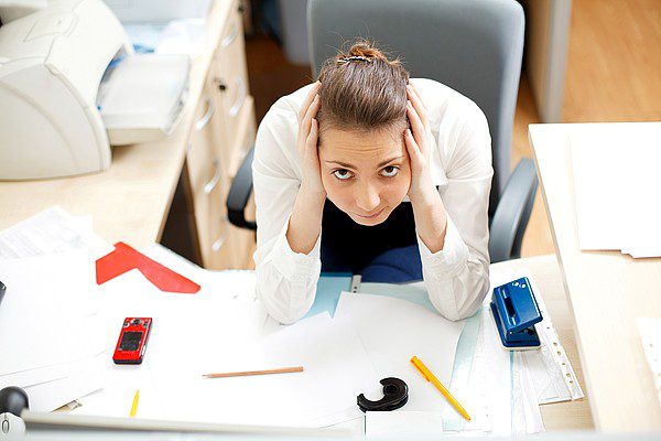 woman holding head over papers