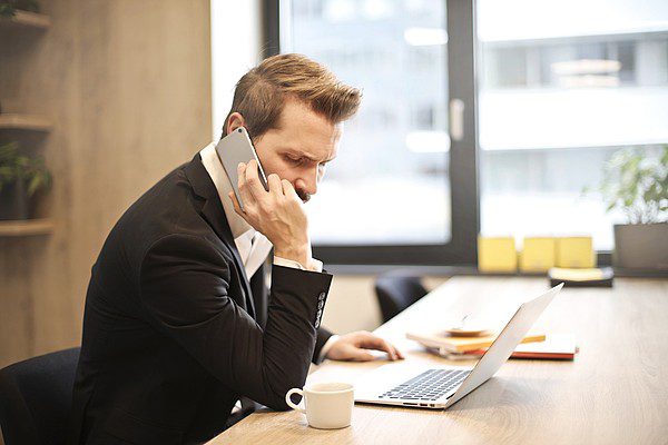 man on call with laptop and coffee on table
